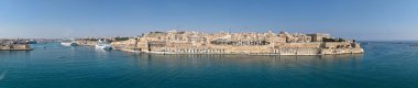 Grand Harbour, Malta 'da bulunan Vallettas' ın geniş hava manzarası, kireçtaşı şehir duvarları, liman binaları ve sakin mavi denizde seyahat gemileri ile güçlendirildi..
