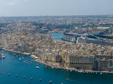 Malta 'nın Gozo kentindeki yoğun bir kıyı kasabasının havadan görünüşü, korunaklı bir limanı, liman binaları ve temiz Akdeniz sularında sayısız küçük teknesi var..