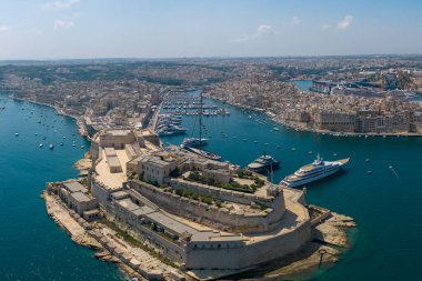 Limanı, adaları ve yarımadaları, yoğun liman binaları ve berrak bir gökyüzü altında sakin mavi denizi olan geniş bir kıyı şehri manzarası..