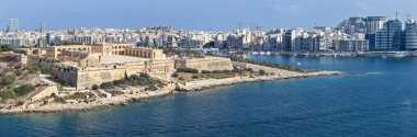 Manoel Adası 'ndaki Manoel Kalesi' nin panoramik manzarası, kireçtaşı kaleleri, Marsamxett Limanı suyu ve SliemaGzira silueti açık yaz ışığı altında..