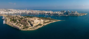Açık gökyüzü altında kumlu yarımadası, marinası ve teknesi olan bir sahil şehrinin hava panoramik manzarası..