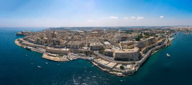 Taş kaleleri, yoğun tarihi binaları, liman rıhtımları ve tekneleri olan, sisli gökyüzünün altında derin mavi denizlerle çevrili, müstahkem bir yarımada şehrinin geniş hava manzarası..