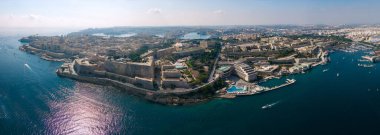 Kıyı kenti ve limanın geniş panoramik manzarası yarımada, mavi deniz, rıhtım ve parlak yaz ışığında tekneler..