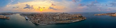 Günbatımında Valletta yarımadası ve Grand Harbour 'un geniş panoramik manzarası, tahkimatlar, yolcu gemisi ve Akdeniz kıyı şeridi.