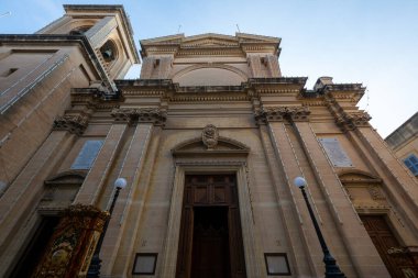 Birgu 'daki (Vittoriosa) Dominik Manastırı' nın düşük açılı görüntüsü, süslü taş pilasterleri, pedikürleri ve açık ahşap kapıları gösteriyor..