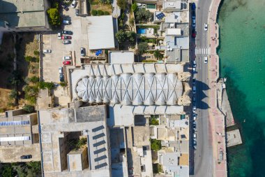 St. Julians, Malta 'daki Carmel Dağı Kilisesi' nin hava manzarası ve yoğun sahil binaları, kıyı yolu ve turkuaz Akdeniz sularının yanında..