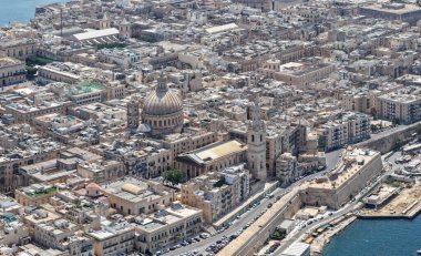 Vallettas 'ın kireçtaşı çatı ve kale duvarlarının belirsiz hava manzarası, Karmelit Kilisesi' nin kubbesi ve limanın yakınındaki yoğun tarihi şehir blokları.