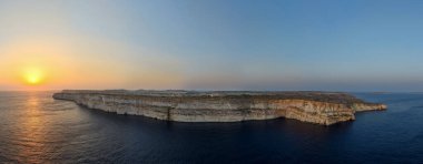 Ta Cenc deniz kayalıklarının Sannat yakınlarındaki panoramik manzarası, Gozo, gün batımında Akdeniz üzerinde katmanlı kireçtaşı yamaçları.