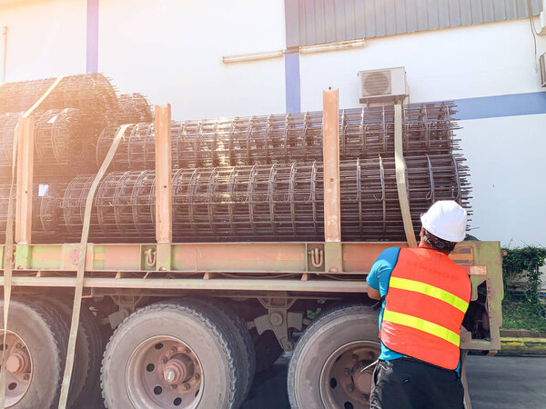 The man was lashing the steel wiremash on the flat bed trailer for distribute to customer