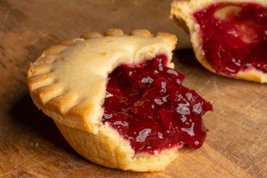 Ahşap masada çilek reçeli dolu yumuşak bisküviler.