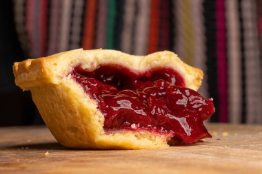 Ahşap masada çilek reçeli dolu yumuşak bisküvi.