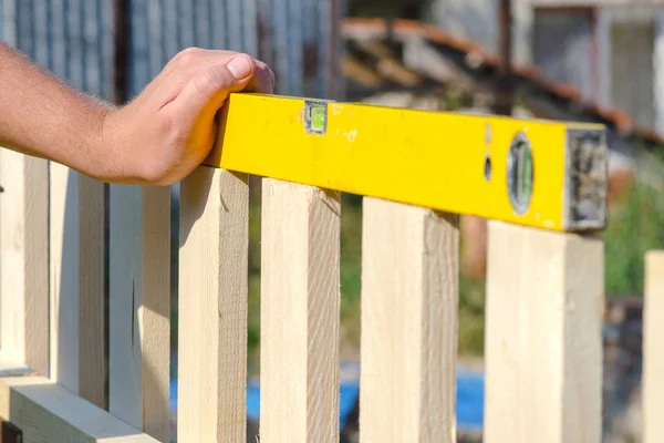 Man een houten hek bouwen en controleren met de waterpas. Clos — Stockfoto