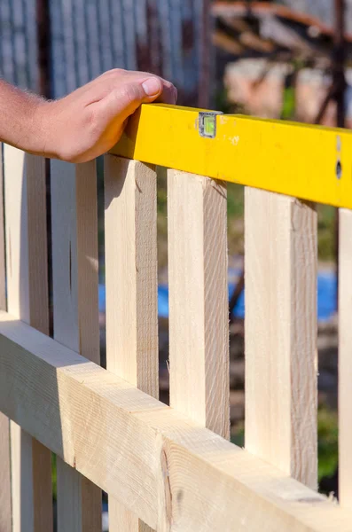 Man een houten hek bouwen en controleren met de waterpas. Clos — Stockfoto