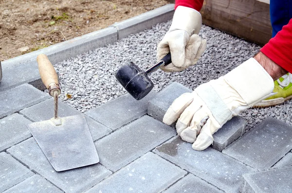 Bricklayer places concrete paving stone blocks for building up a — Stock Photo, Image