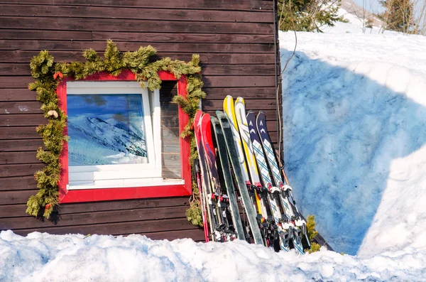 Venster van hut berghut met reflecties van hill en skiis — Stockfoto