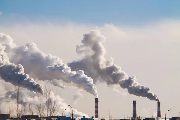 Cheminées industrielles avec une forte fumée causant la pollution de l'air sur le fond bleu ciel — Photo