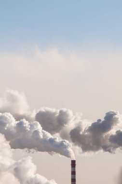 Uzayı sanayi bacalarından çıkan ağır dumanla dikey pankarta kopyalamak mavi gökyüzü arka planında hava kirliliğine neden olur