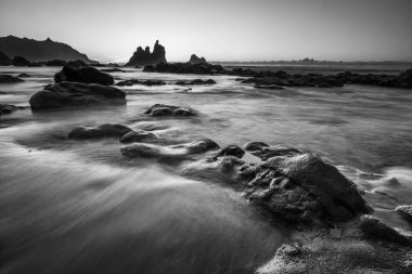 Denizin üzerinde güzel bir gün batımı, kum, dalgalar ve uçurumlar. siyah ve beyaz resim