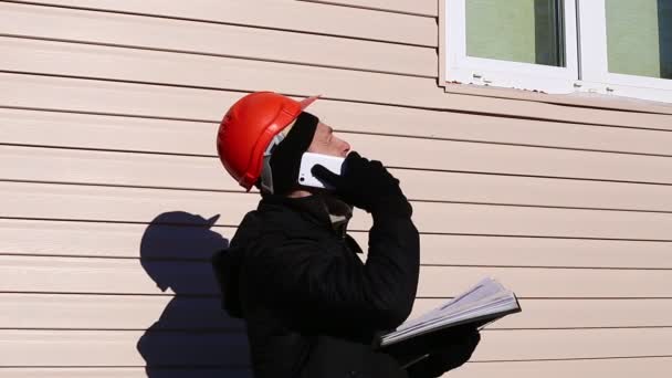 Arbeiter im Winter auf einer Baustelle im Gespräch mit dem Smartphone — Stockvideo