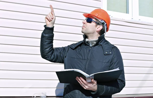 Trabajador en un sitio de construcción en invierno mira el dibujo — Foto de Stock
