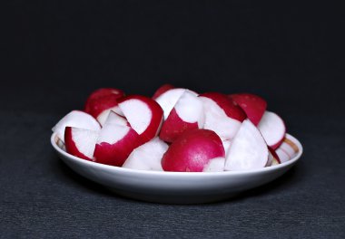 Bir plaka üzerinde kırmızı taze turp dilimlenmiş