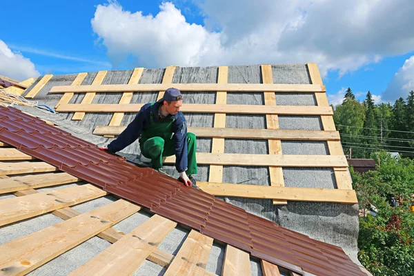 Worker puts the metal tiles on the roof — Stock Photo, Image