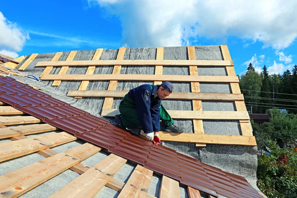 Lavoratore mette le piastrelle metalliche sul tetto — Foto Stock