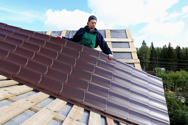 Arbeiter legt die Metallziegel aufs Dach Stockbild
