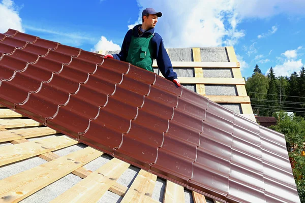 Arbeiter legt die Metallziegel aufs Dach lizenzfreie Stockfotos