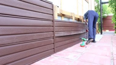 İşçi plastik siding evin cephesinde yükler.