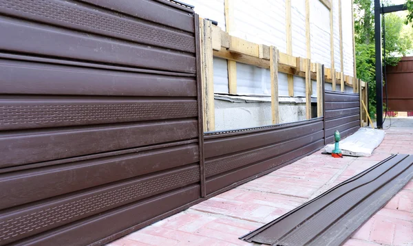 Монтаж коричневого пластикового сайдинга на фасаді — стокове фото