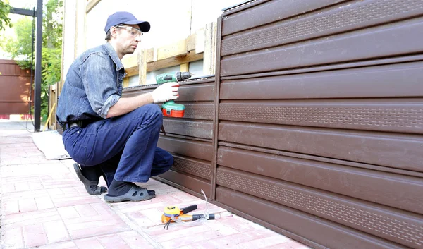 Arbeiter montiert Kunststoff-Abstellgleis an Hausfassade — Stockfoto