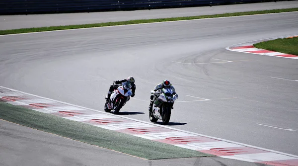 Dois pilotos em uma motocicleta passeios na velocidade da pista — Fotografia de Stock