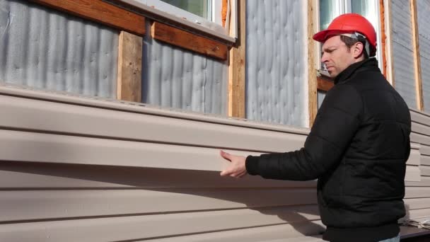 Ein Arbeiter installiert Paneele beige Abstellgleis an der Fassade — Stockvideo