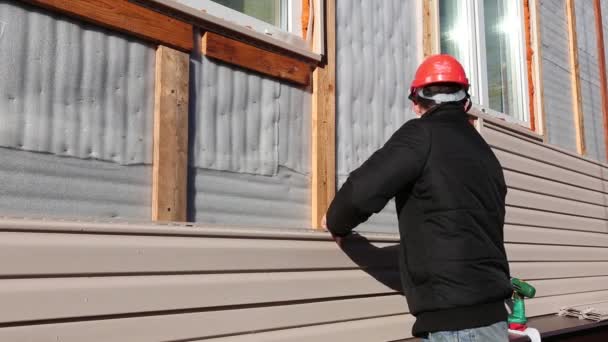 En arbetstagare installerar panelerna beige ytterväggar på fasaden — Stockvideo