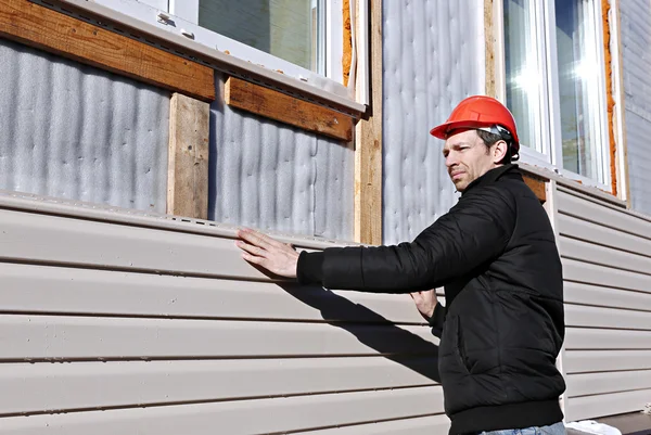 Een werknemer installeert panelen beige siding op de gevel — Stockfoto