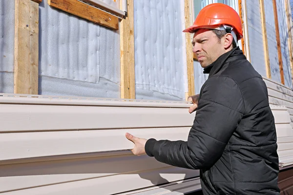 Un travailleur installe des panneaux de revêtement beige sur la façade — Photo