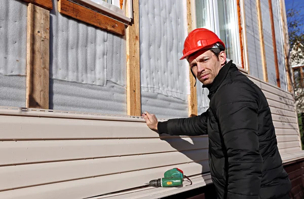 En arbetstagare installerar panelerna beige ytterväggar på fasaden — Stockfoto