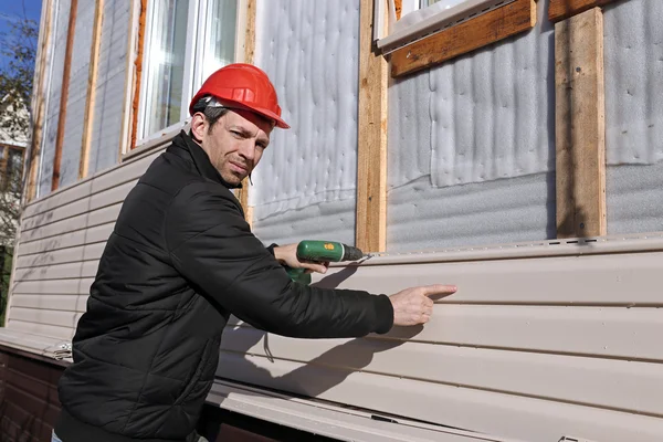 Een werknemer installeert panelen beige siding op de gevel — Stockfoto