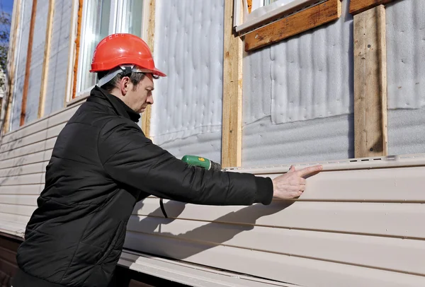 Un trabajador instala paneles de revestimiento beige en la fachada — Foto de Stock