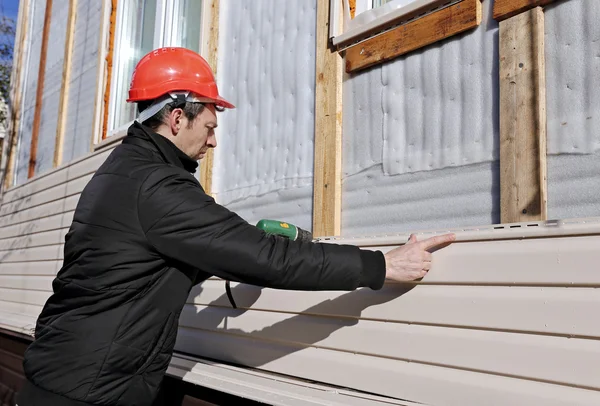 Un travailleur installe des panneaux de revêtement beige sur la façade — Photo