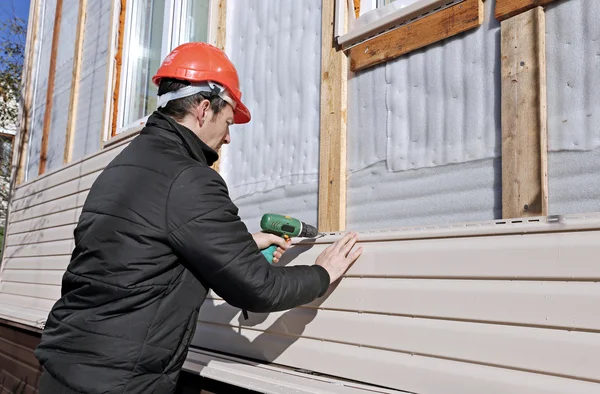 Pracownik instaluje beżowy panele siding na elewacji — Zdjęcie stockowe