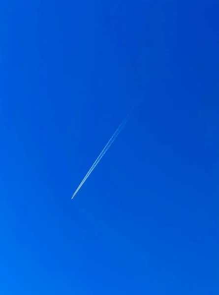 Ein Vorbeifliegendes Düsenflugzeug Hinterlässt Ein Helles Kondensstreifen Vor Tiefblauem Himmel — Stockfoto