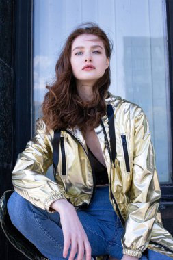 Pencerenin önünde rüzgarlı ve siyah saçlı altın pelerinli beyaz kız portresi