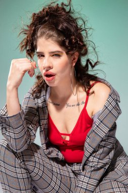 Kırmızı elbiseli beyaz Avrupalı manken, yeşil renkte izole edilmiş yüzünün yanında oturuyor.