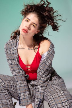 Takım elbiseli beyaz Avrupalı kız model yeşil alanda tek başına oturuyor.