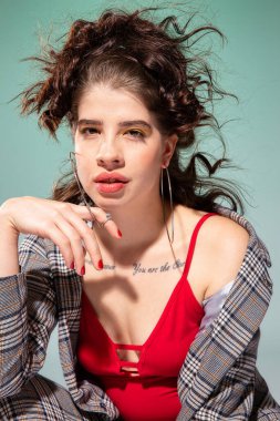 Kırmızı elbiseli beyaz Avrupalı kız model yeşil üzerinde tek başına oturuyor.