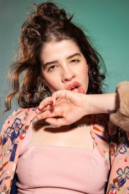 Siyah saçlı, koca dudaklı, beyaz bir kadın. El, yeşil üzerinde izole edilmiş yüz portresinin yanında.