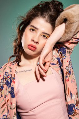 Yüzünün yanında eli olan, koyu renk saçlı, yeşil dudaklı beyaz bir kadın.