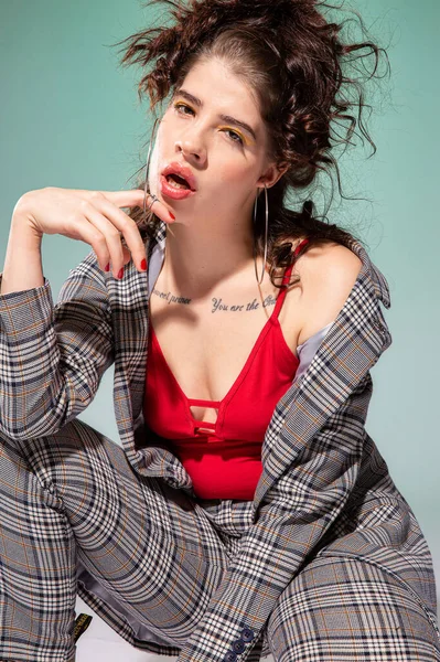 Kırmızı elbiseli beyaz Avrupalı manken, yeşil renkte izole edilmiş yüzünün yanında oturuyor.